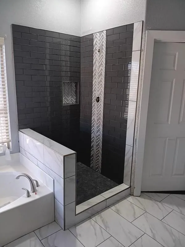 Black subway tile shower with chevron mosaic accent strip and marble look floor Phoenix AZ