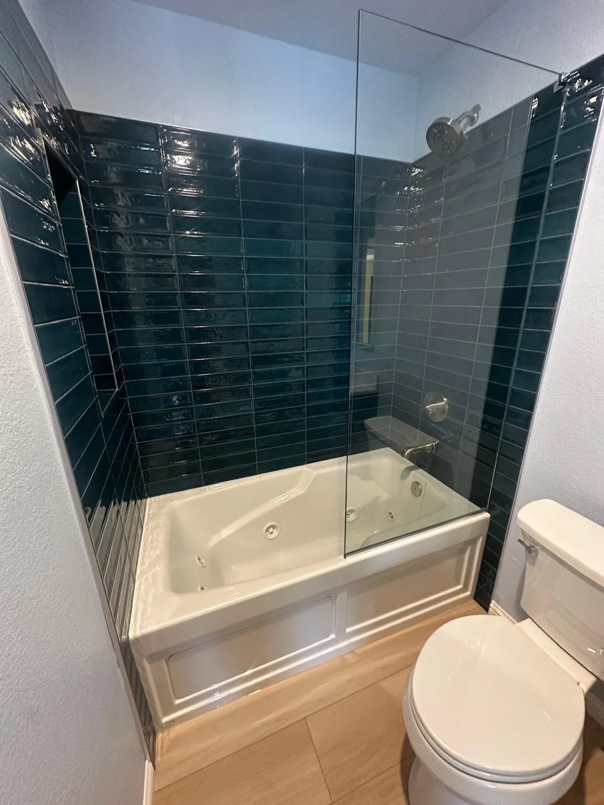 Bathroom remodel with glossy deep blue subway tile jetted bathtub shower combo and frameless glass panel Phoenix AZ