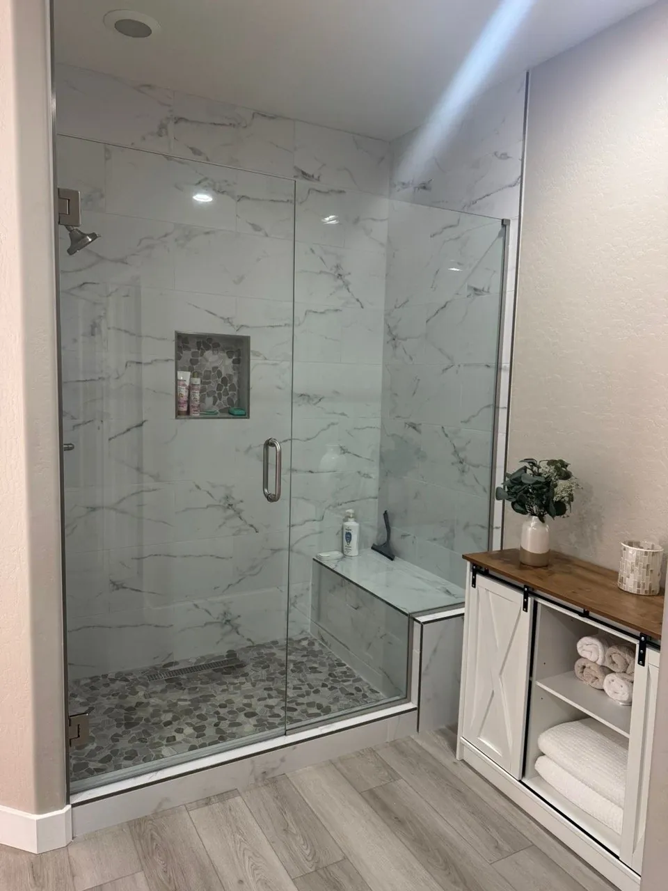 Carrara marble look tile walk-in shower with frameless glass door built-in bench pebble mosaic floor Phoenix AZ