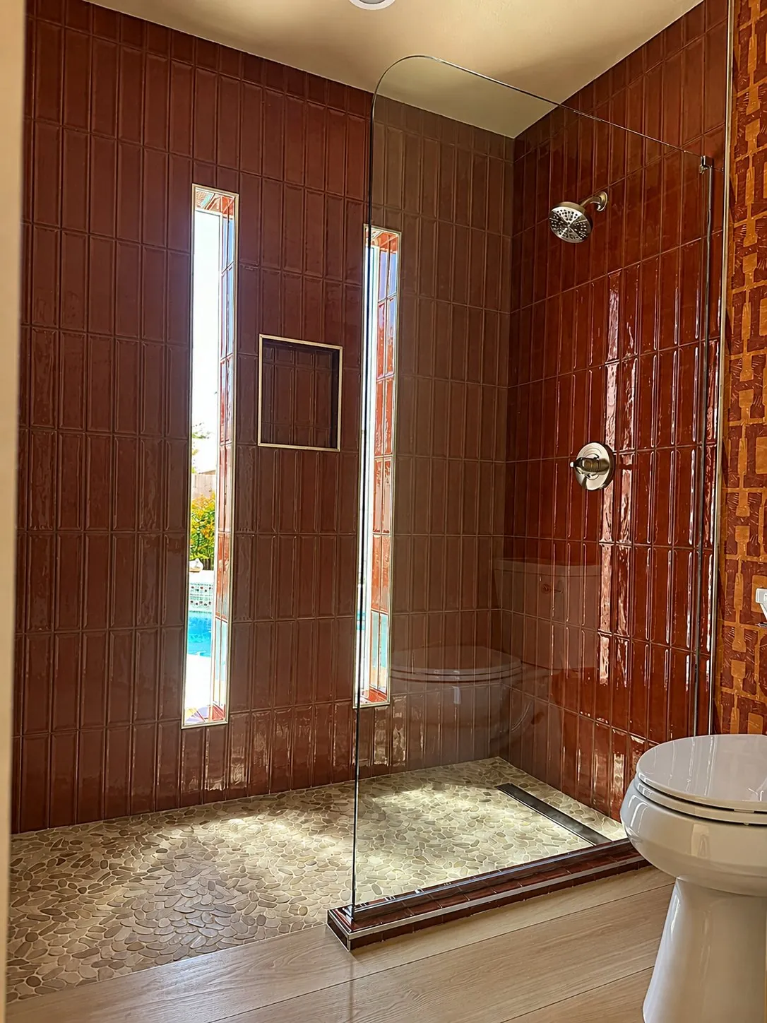 Glossy terracotta subway tile walk-in shower with glass panel and window slits Phoenix AZ