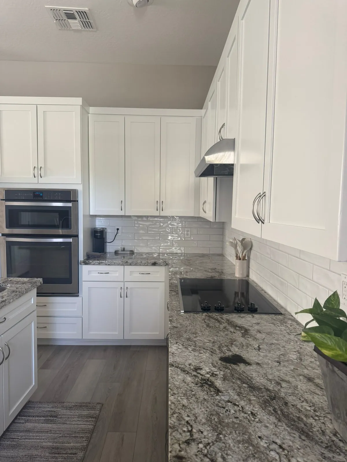 White glossy subway tile backsplash over granite countertops and a cooktop, installed by RDC in a Mesa, AZ kitchen