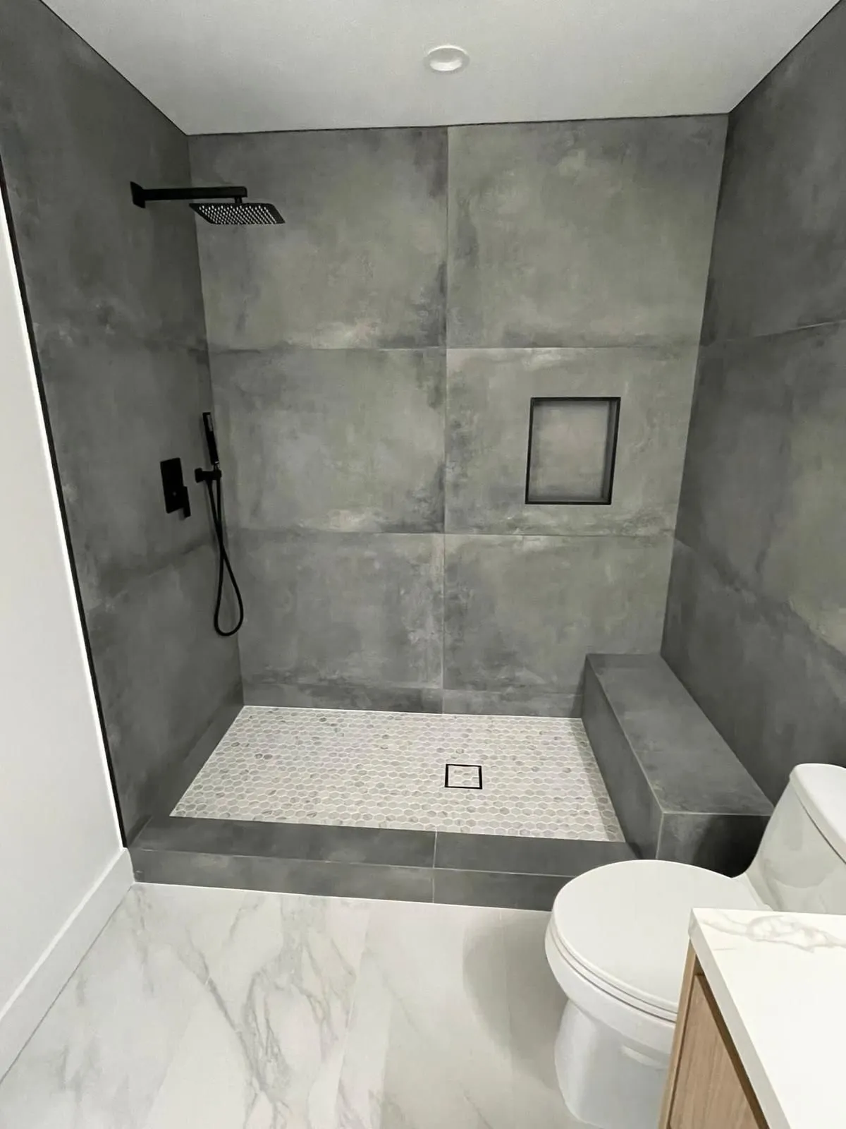 Walk-in tile shower with a built-in bench and black fixtures, built by RDC in the Phoenix area