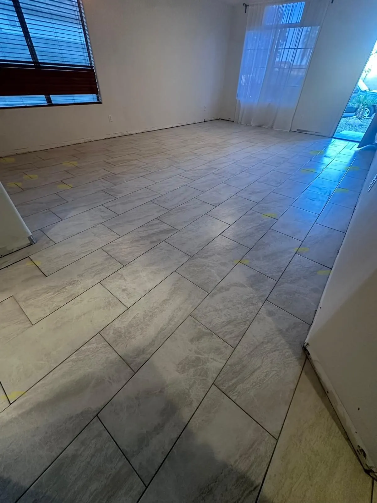 Large format gray porcelain tile floor installation in brick pattern living room Phoenix AZ by RDC Renovation