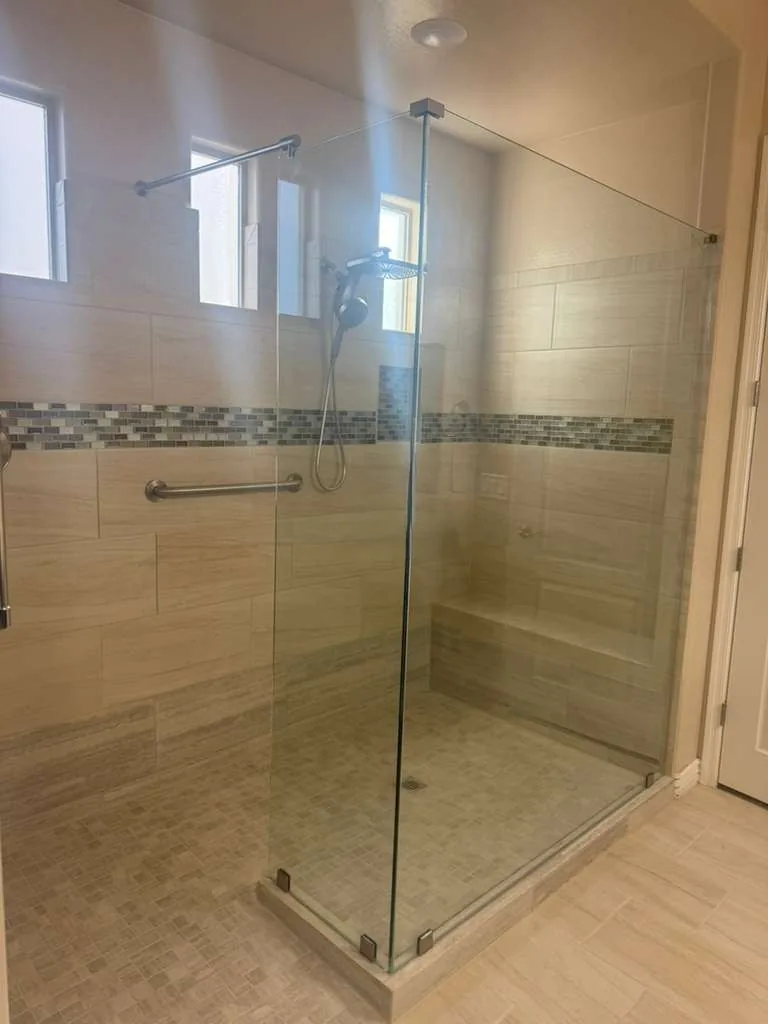 Low-step walk-in glass shower with a mosaic accent band, bench and grab bar, built by RDC Renovation in Phoenix, AZ