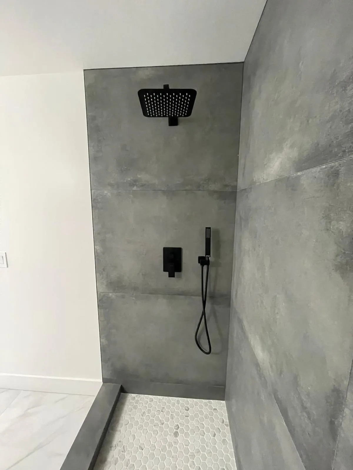 Modern gray large format tile walk-in shower with matte black fixtures and no door by RDC Renovation in Phoenix AZ