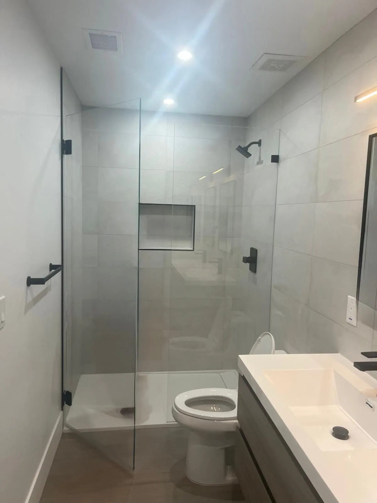 Modern bathroom remodel with large format gray tile walk-in shower matte black fixtures frameless glass and floating vanity Phoenix AZ