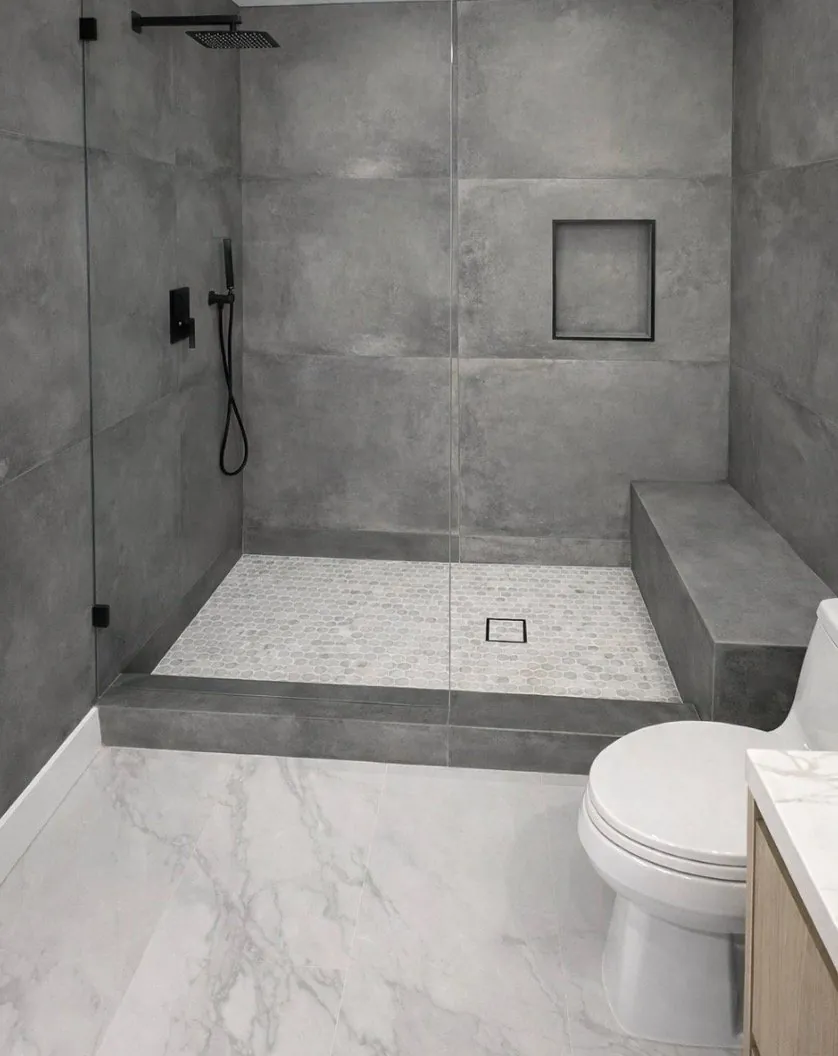 Modern bathroom remodel with large format concrete-look tile shower matte black fixtures bench seat and marble floor Phoenix AZ