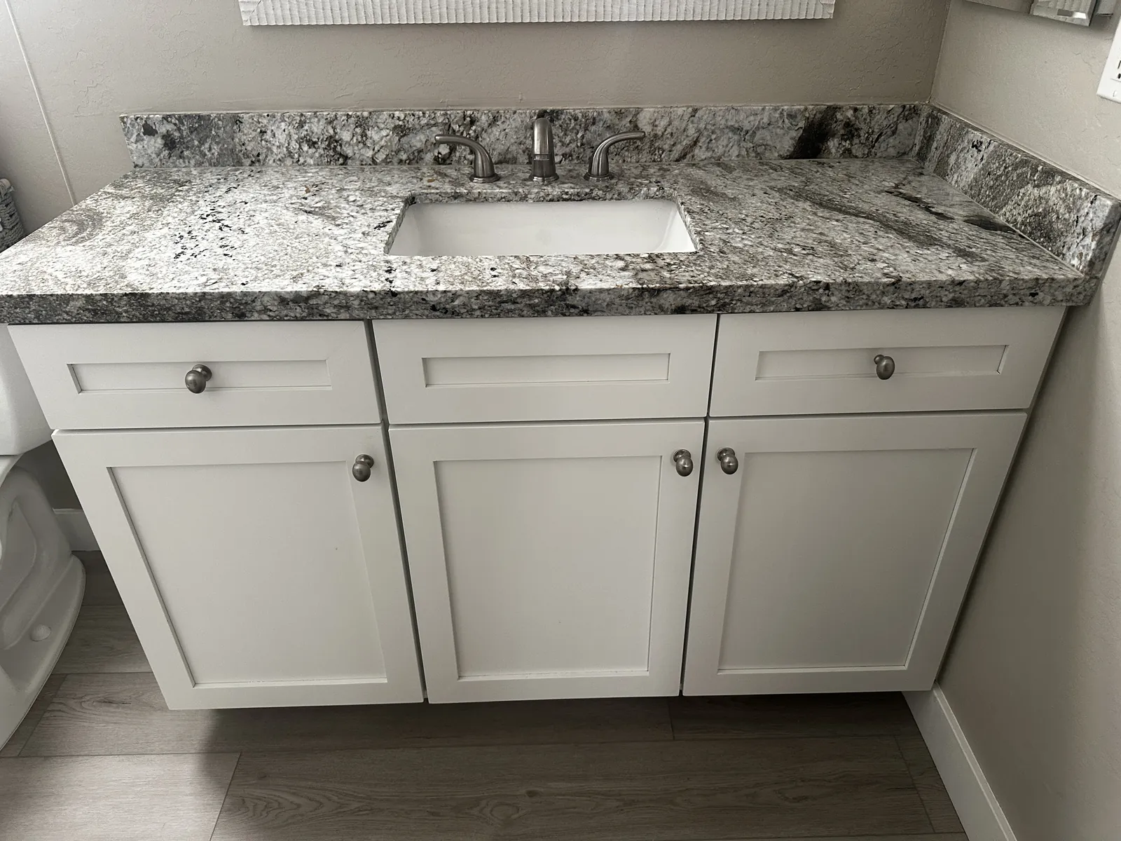 Old granite vanity top on a white cabinet in a Mesa, AZ bathroom before countertop replacement by RDC Renovation