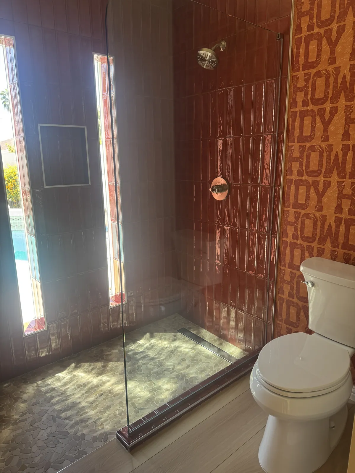 Terracotta tile walk-in shower with pebble stone floor and glass panel in a Phoenix AZ bathroom remodel by RDC Renovation