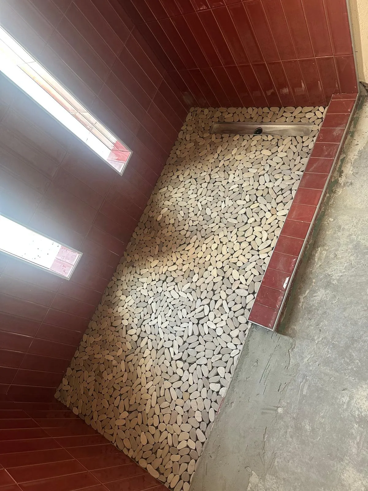 Custom tile shower under construction: terracotta wall tile and a pebble floor going in, Phoenix AZ