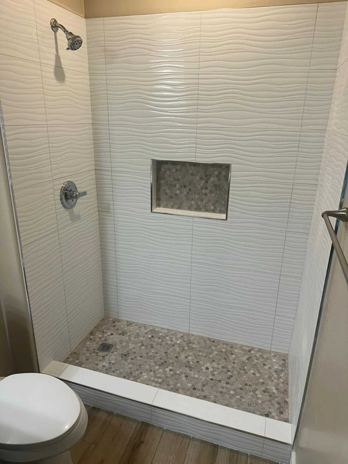 The same Phoenix, AZ bathroom after RDC's conversion: white wave tile shower, hexagon mosaic floor and niche