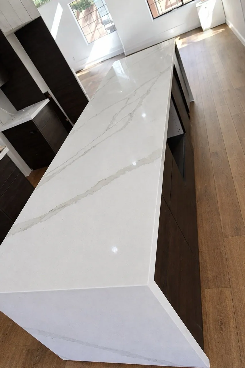 White Calacatta quartz kitchen island countertop with waterfall edge dark wood cabinets and hardwood flooring Phoenix AZ