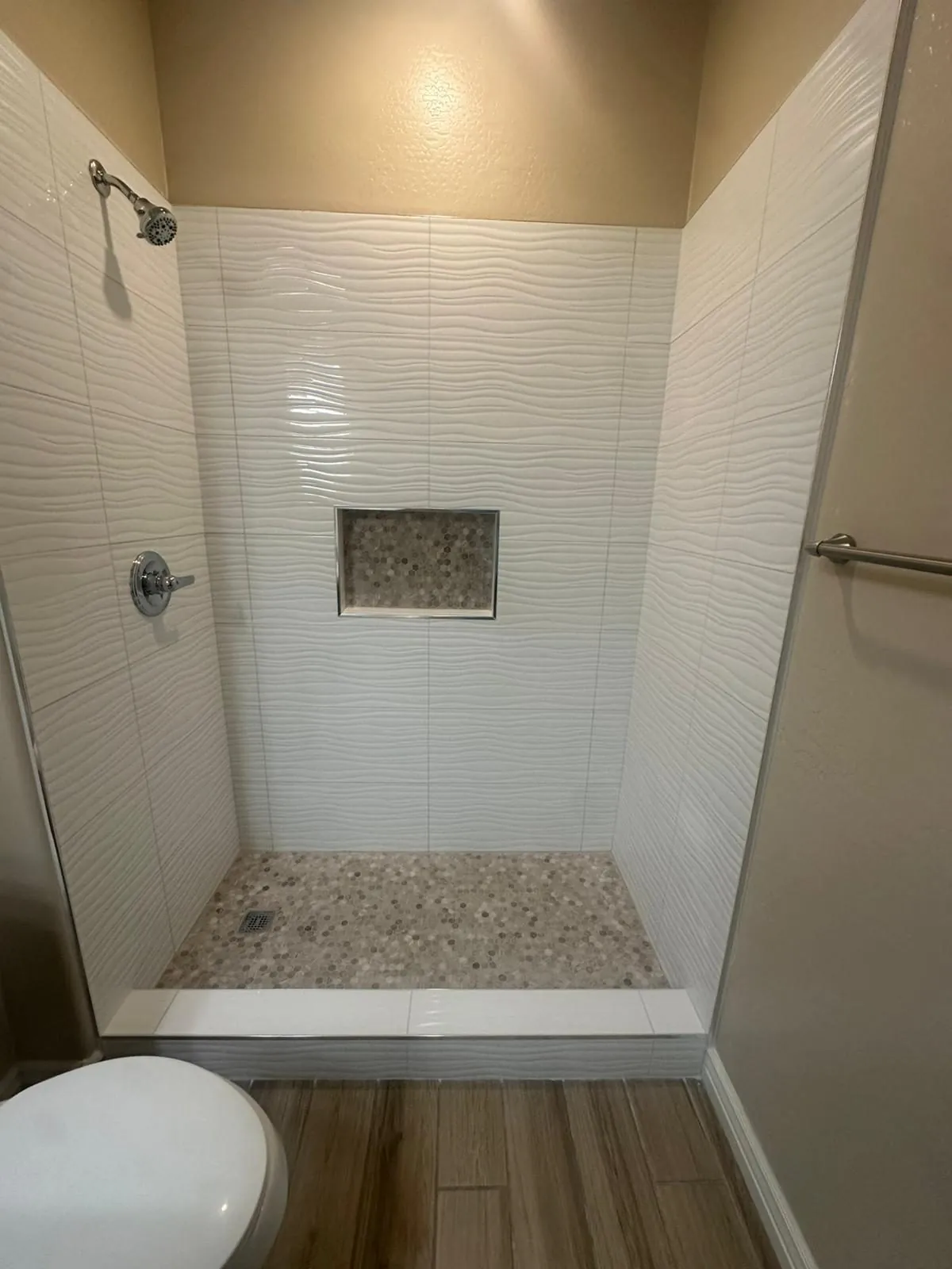 Shower remodel with white 3D wave texture tile penny round mosaic floor and chrome fixtures Phoenix AZ